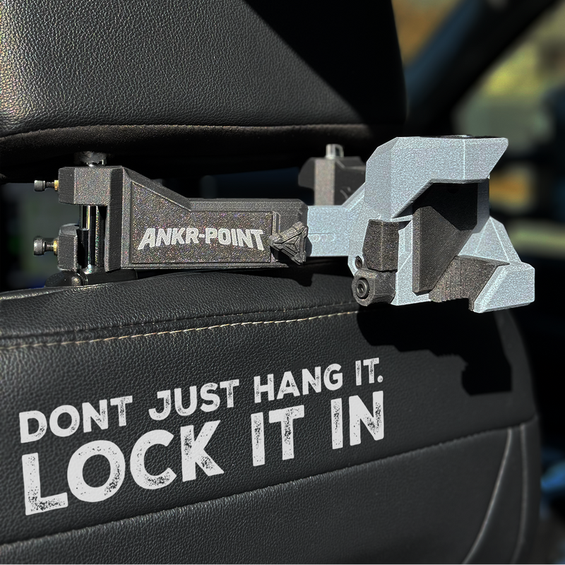 Carabiner with 'Ankr-Point' branding attached to a car seat, with text 'Don't just hang it. Lock it in'.